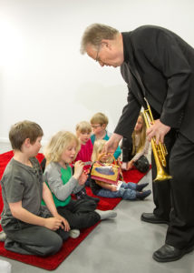 Barn som sitter på golvet och musikern Bengt Fagerström